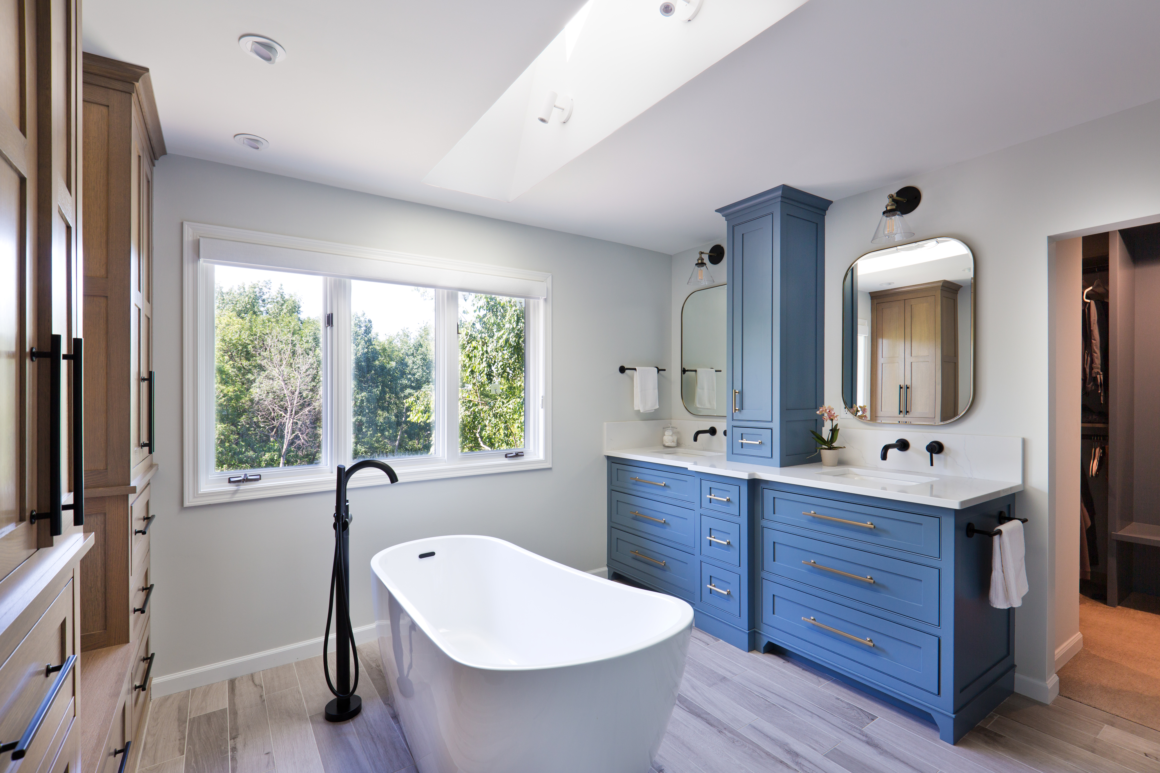 Modern bathroom with a standalone tub, blue vanity cabinets, and a large mirror