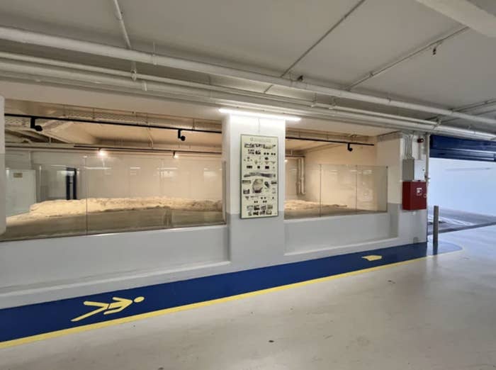 Exhibit with artifacts behind glass and informational panel in a parking garage setting