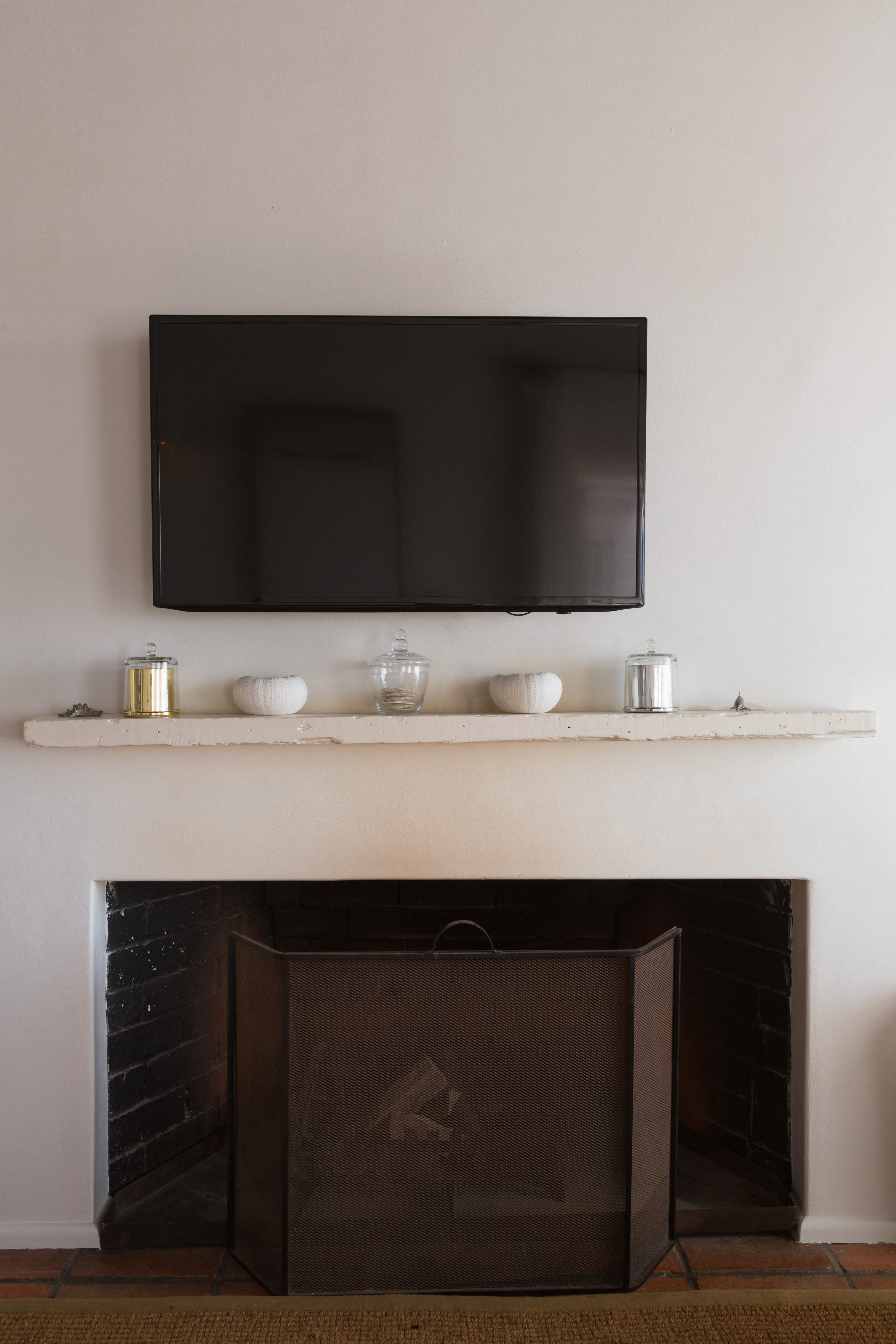 Fireplace with a mounted TV above, decorative candles on the mantle, and a protective screen