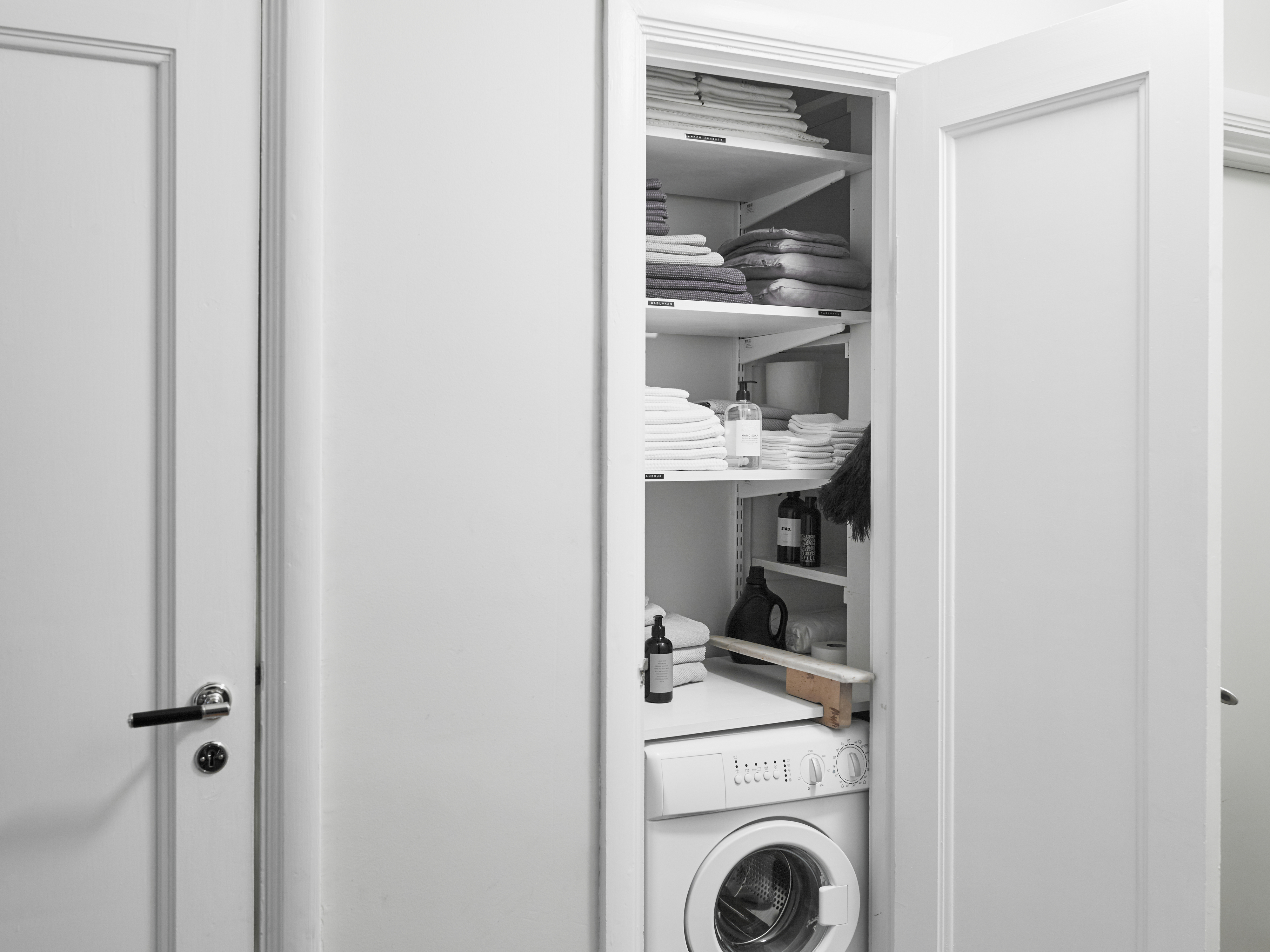 An open closet with organized shelves, towels, and a washing machine