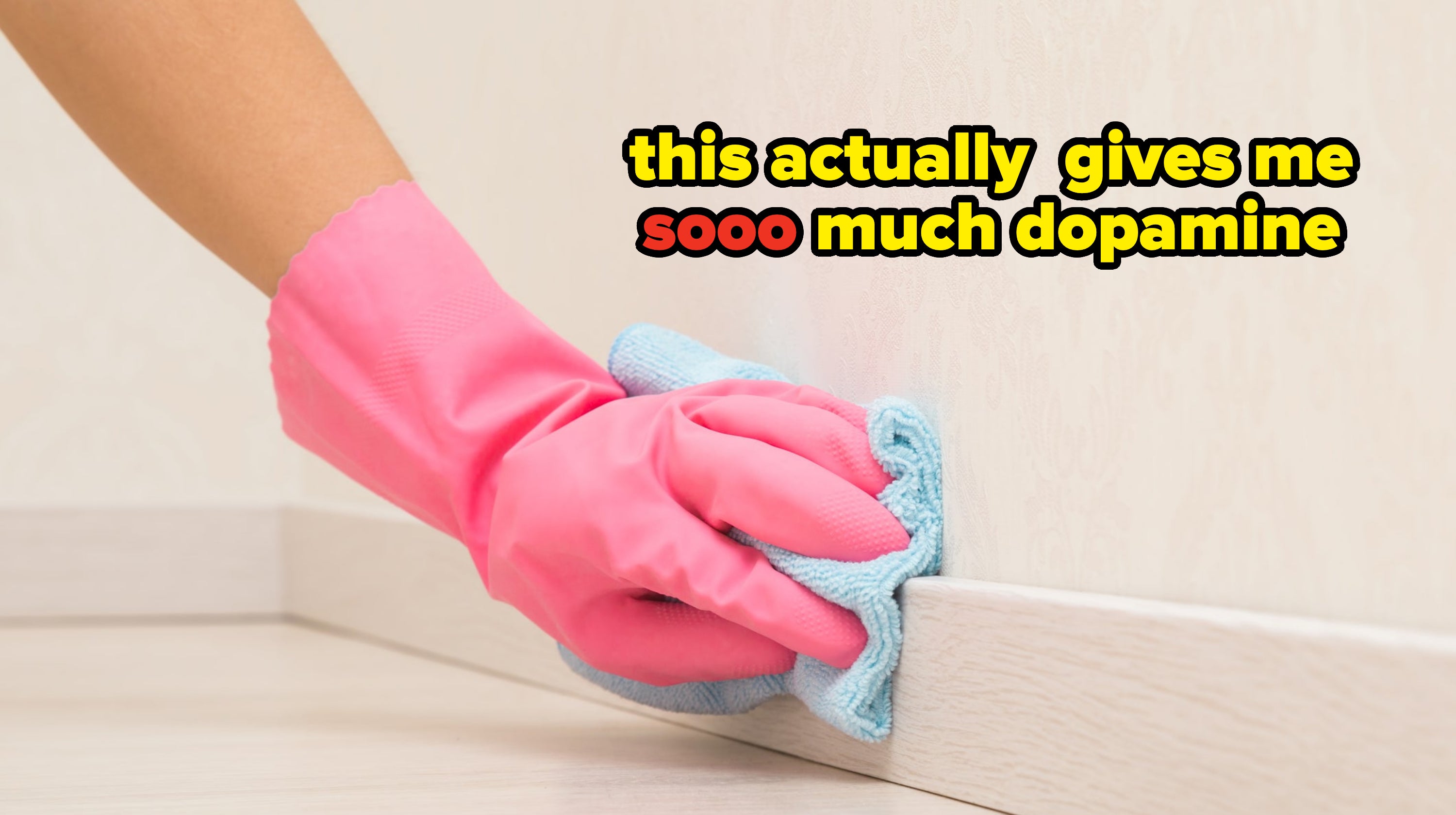 Hand in pink gloves cleaning a baseboard with a blue cloth, text reading, this actually gives me soo much dopamine