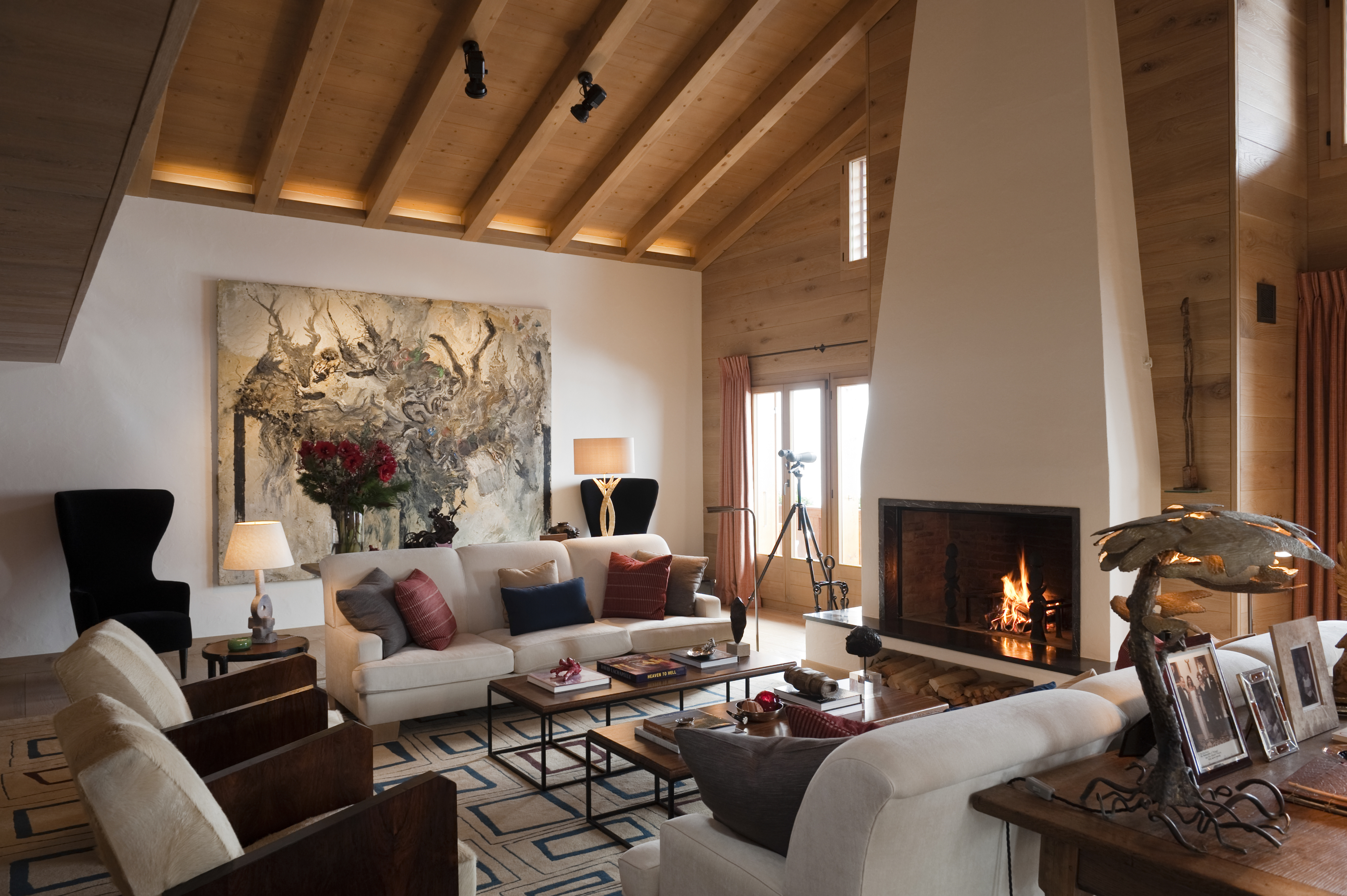 Cozy living room with a lit fireplace, sofas, and wooden beams on the ceiling