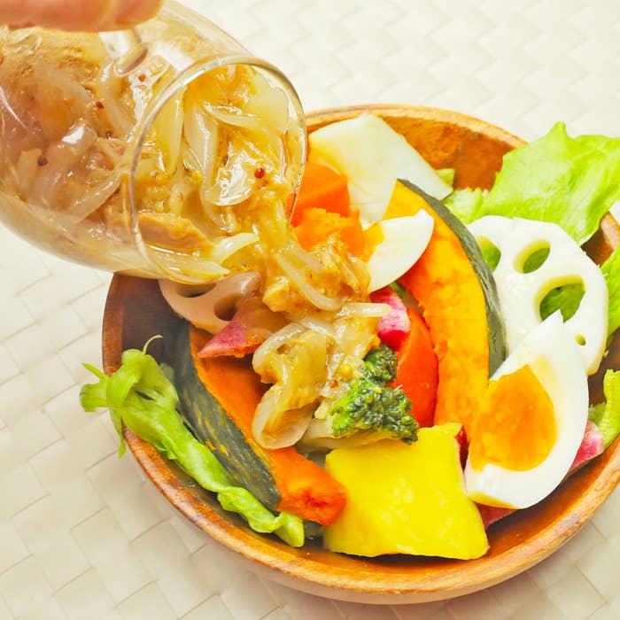 野菜と温泉卵が入ったサラダにドレッシングをかける様子。