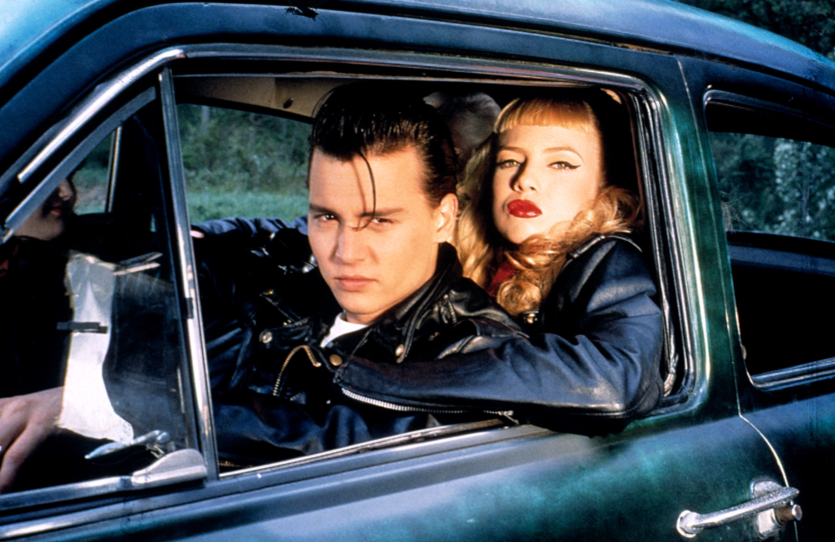 Johnny Depp and Traci Lords in &#x27;Cry-Baby,&#x27; dressed in 50s style, sitting in a vintage car