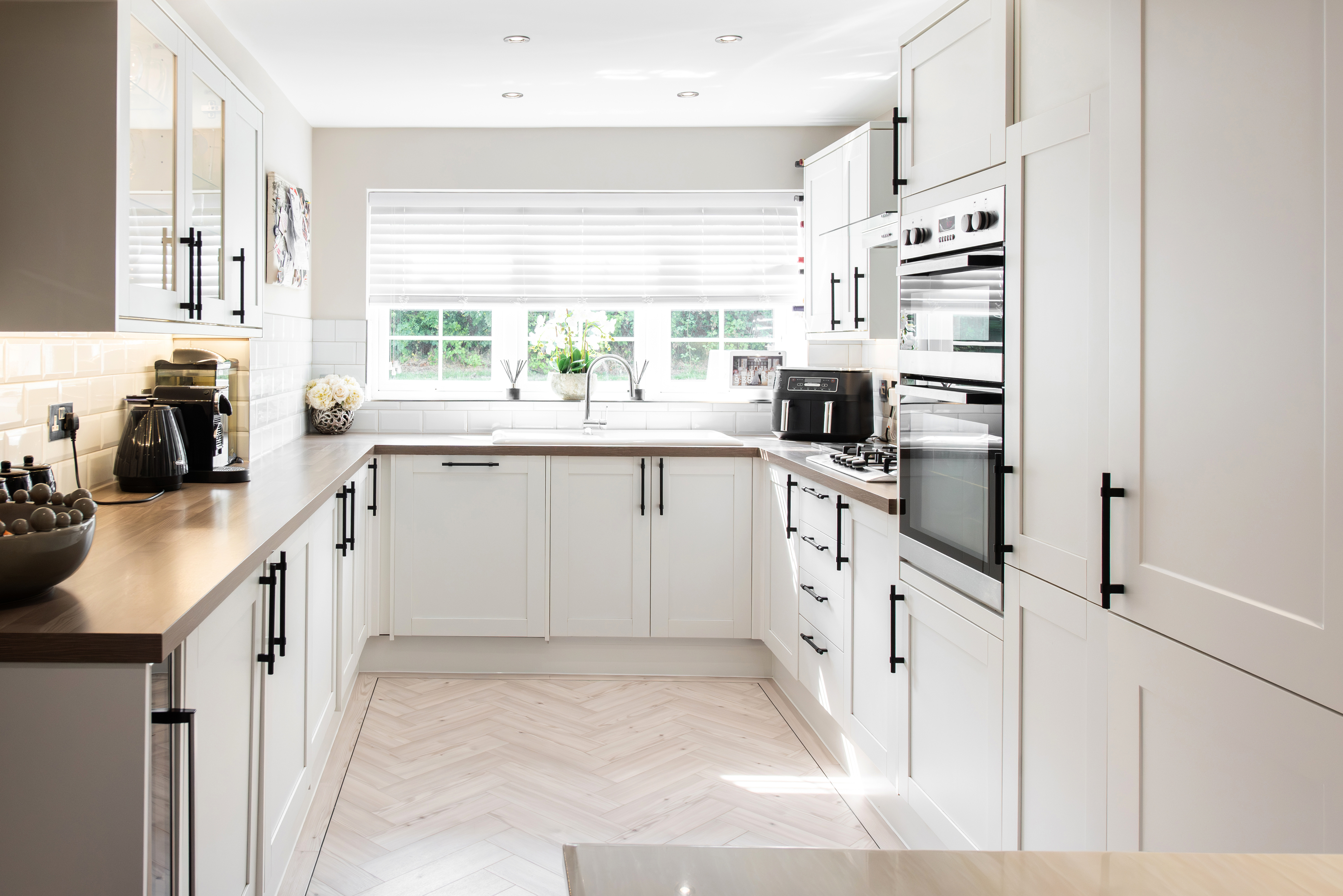 Modern kitchen with white cabinetry, appliances, and a herringbone floor pattern