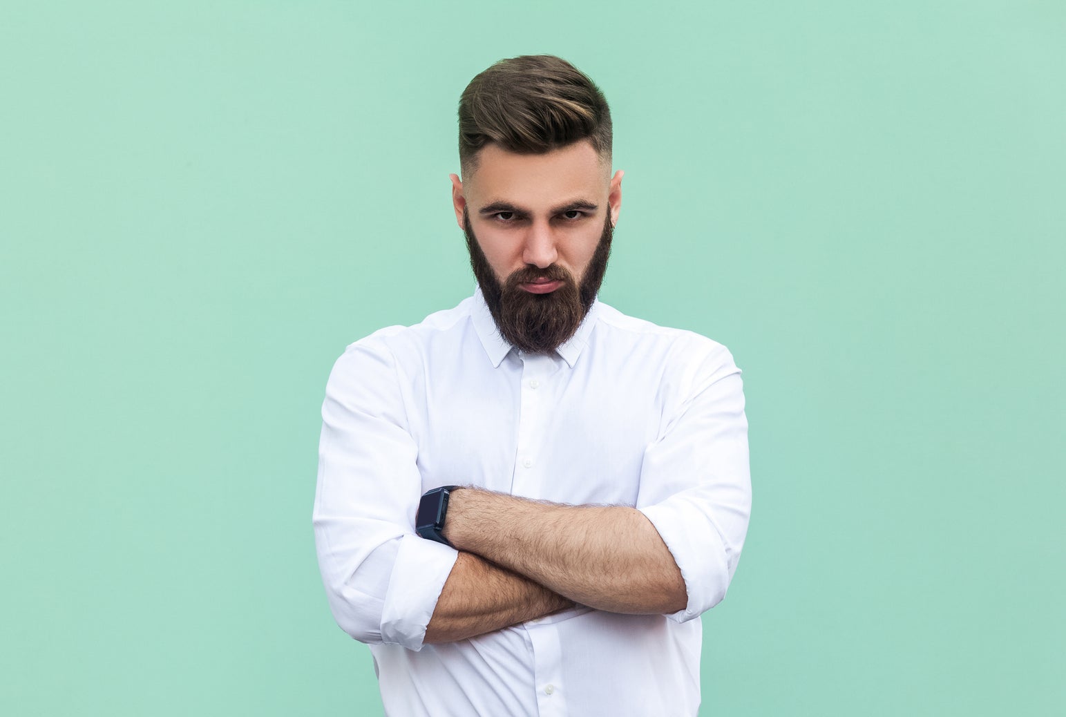 Man with beard, arms crossed, in button-up shirt and trousers, exudes confidence