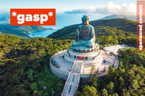 Aerial view of the Tian Tan Buddha statue surrounded by mountains and ocean