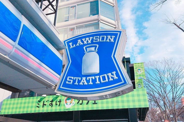 ローソンコンビニの看板と緑のストライプの日除けがある店舗の入り口です。