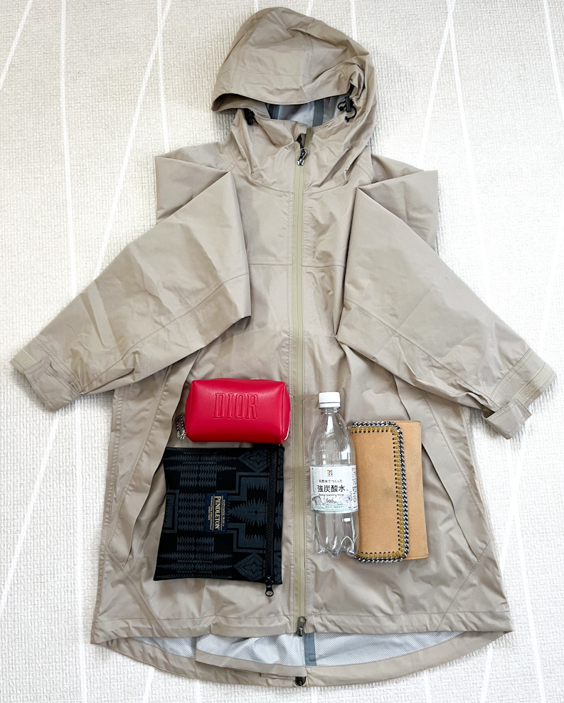 コートの上に赤い財布、ボトル、ノートが置かれています。