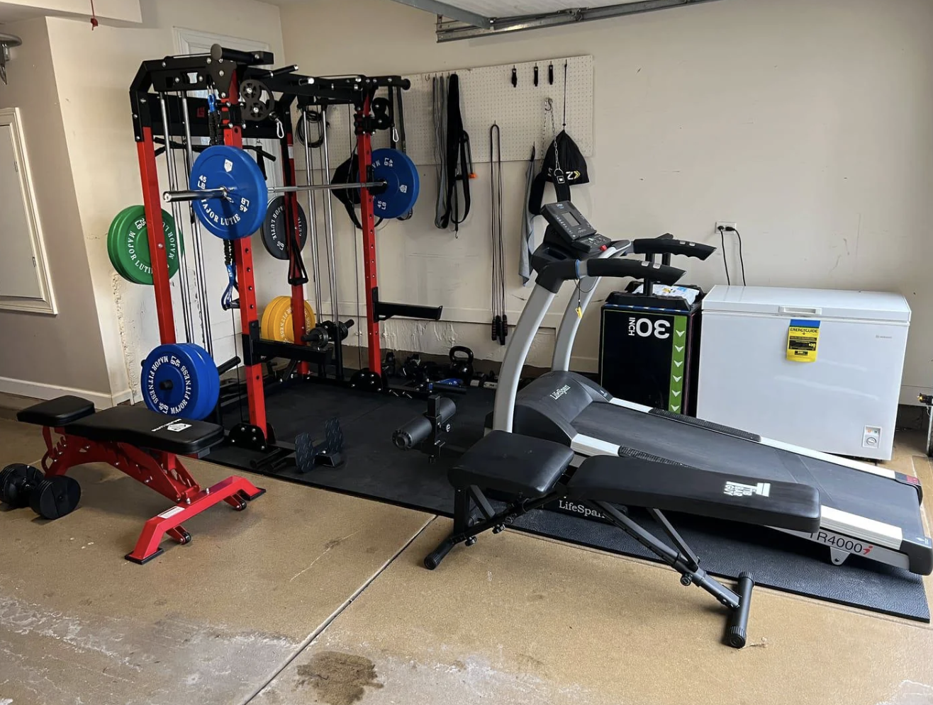 Home gym setup with various exercise equipment including a treadmill, weights, and bench