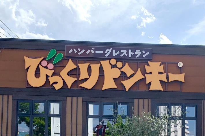 ベジタブルレストランの看板が掲げられた建物の前にトラクターが置かれている。