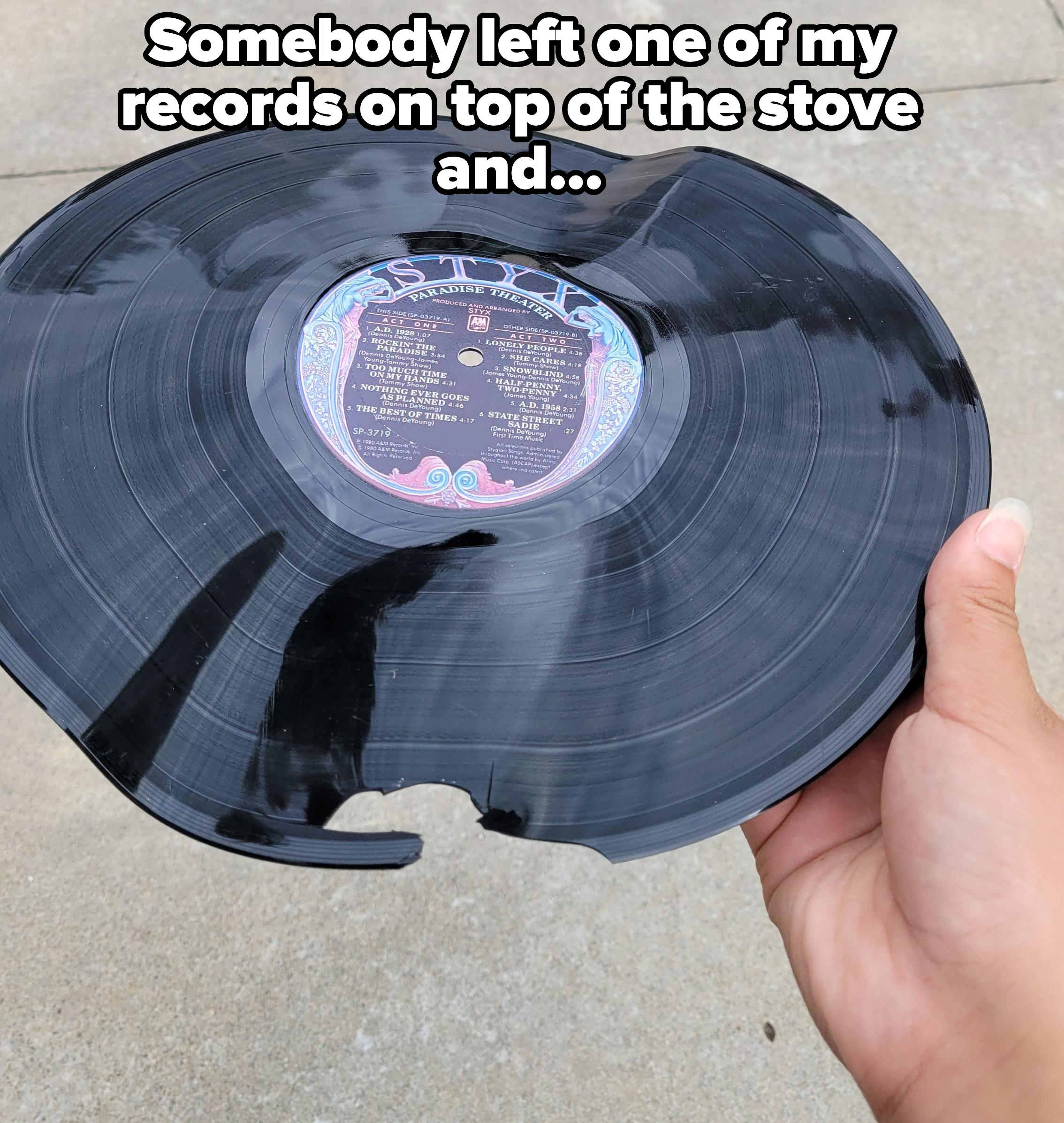 A hand holding a damaged, partially melted LP record that was left on a stove
