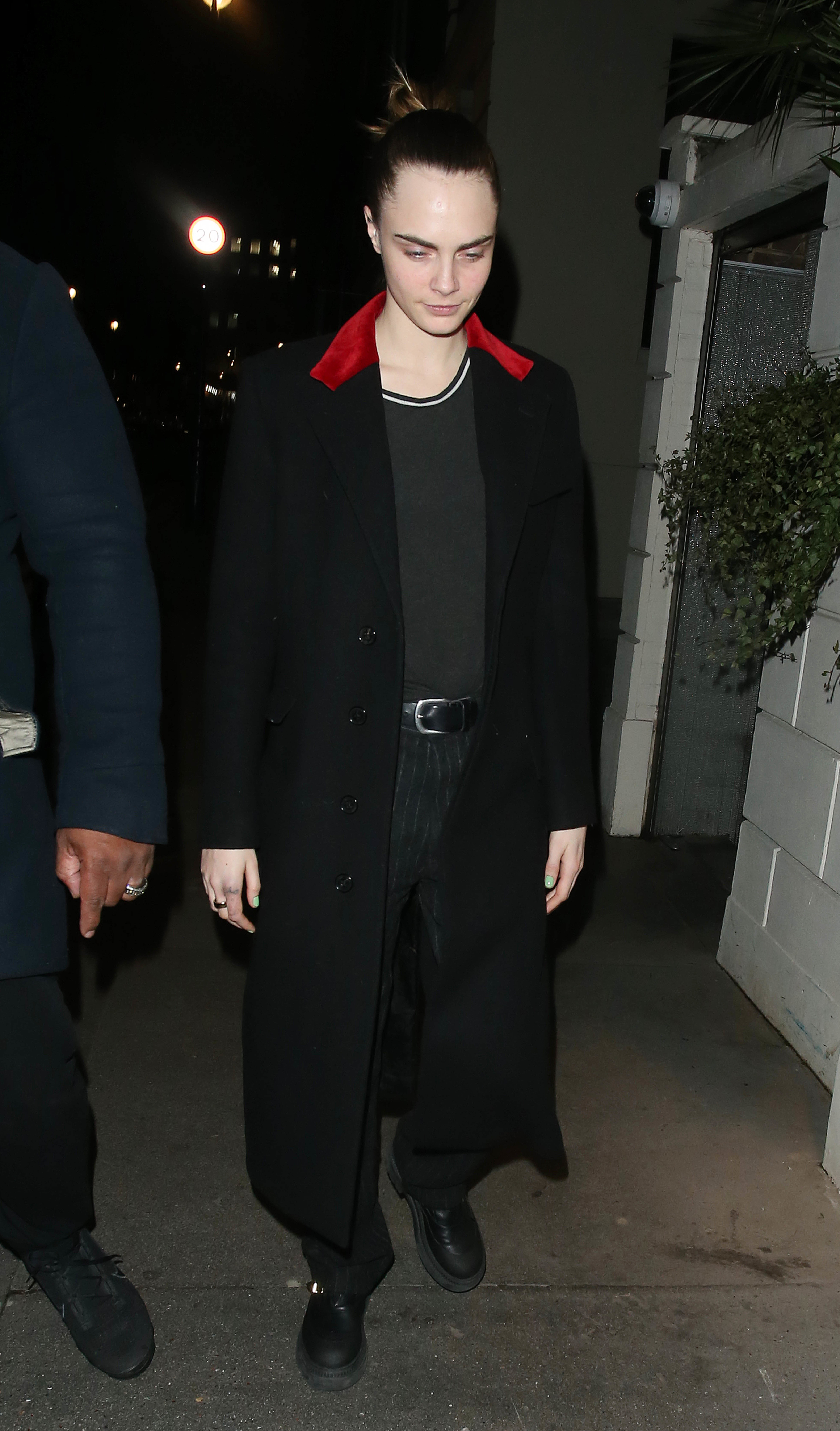 Cara Delevingne in a long coat walks outside at night