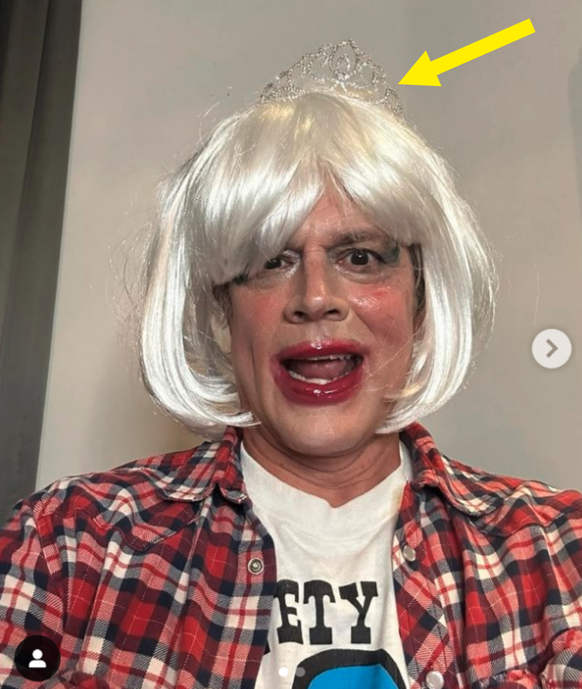 Johnny wearing a wig and tiara, plaid shirt over a t-shirt, with makeup on