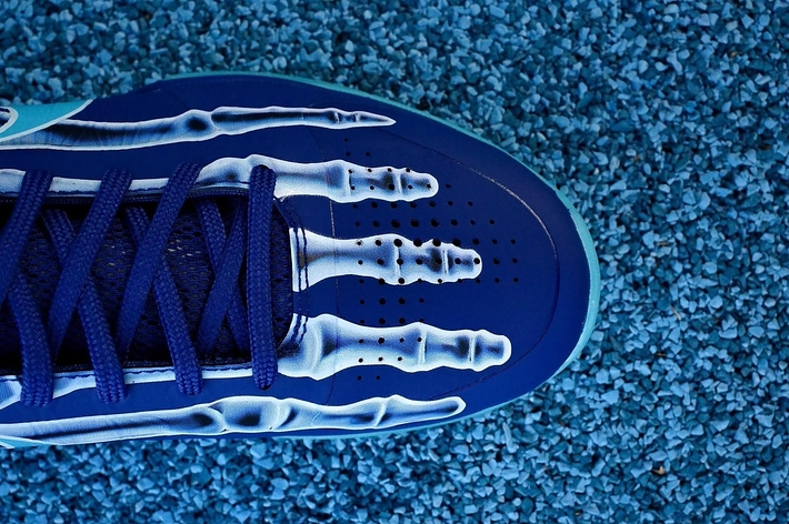 Close-up of a blue sneaker with white laces on a textured surface, highlighting the shoe's design