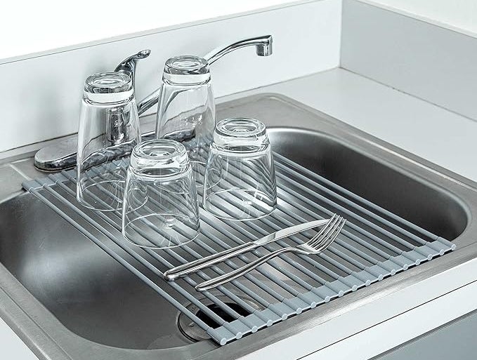 the rack with clean glassware and utensils on it over a sink