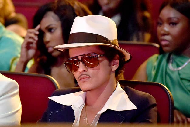 Bruno Mars in white hat and dark suit at a music award event