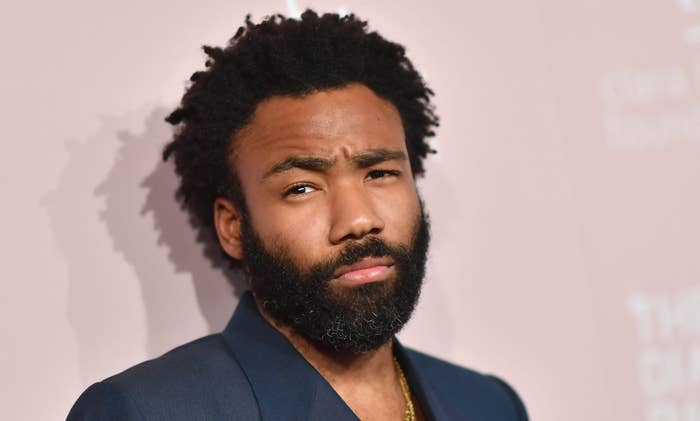 Donald Glover in a navy suit poses on the red carpet