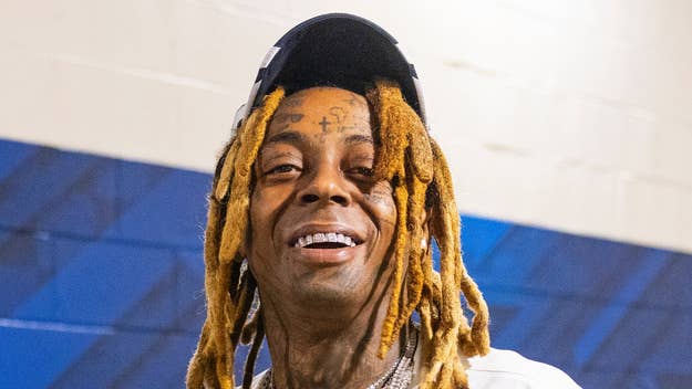 Lil Wayne smiling with sunglasses on his head and face tattoos visible