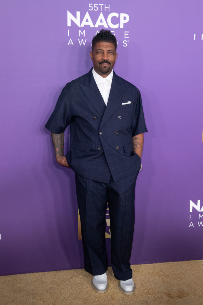 Deon Cole in a double-breasted pinstripe suit posing at the NAACP Image Awards