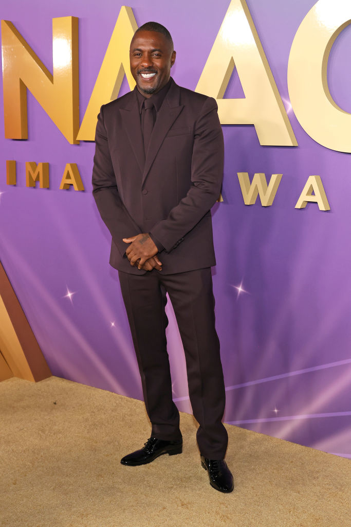 Idris Elba in a tailored suit posing with hands in pockets at the NAACP Image Awards
