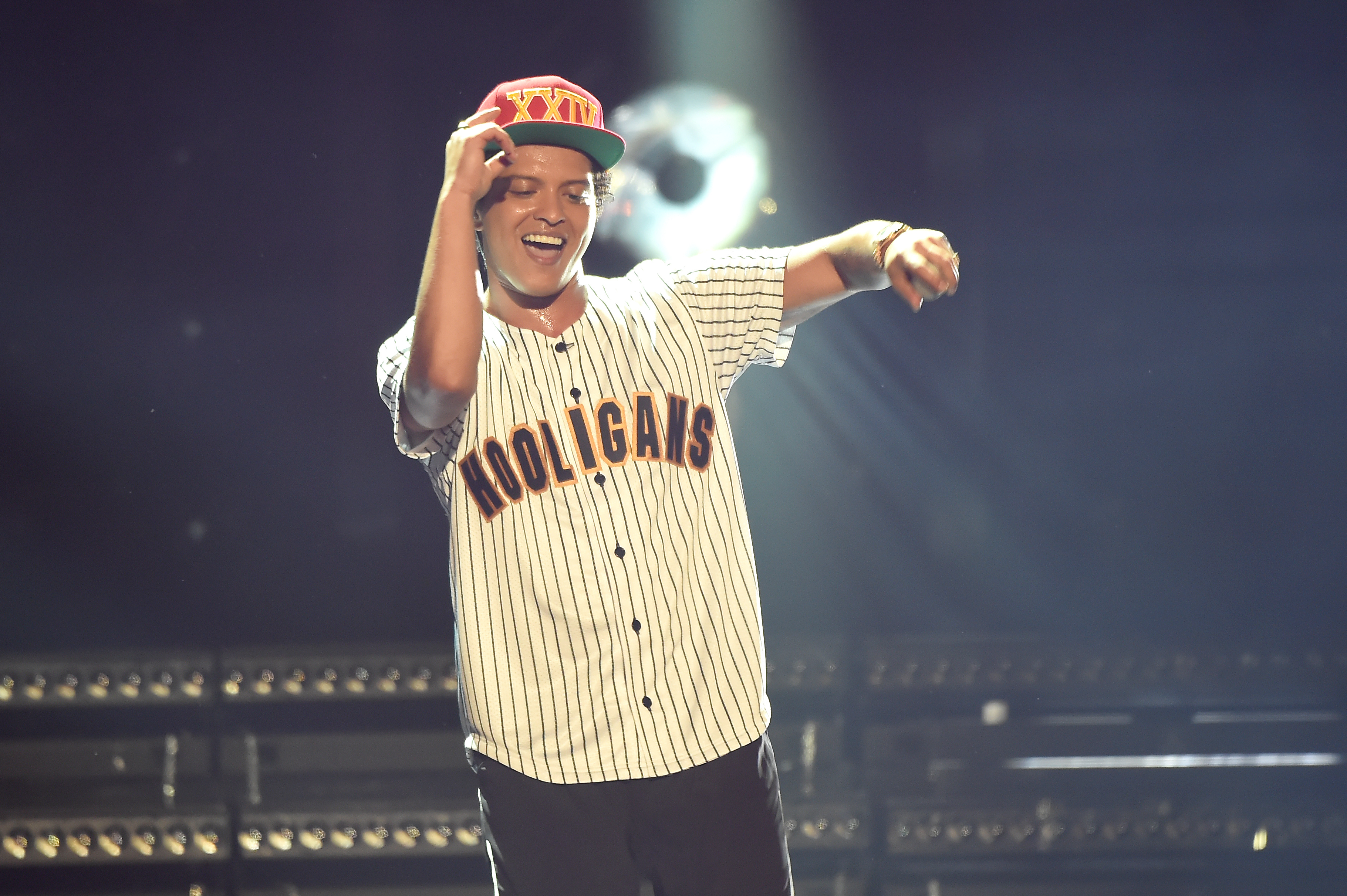 Bruno Mars in a &#x27;Hooligans&#x27; baseball jersey and cap, performing on stage with a microphone