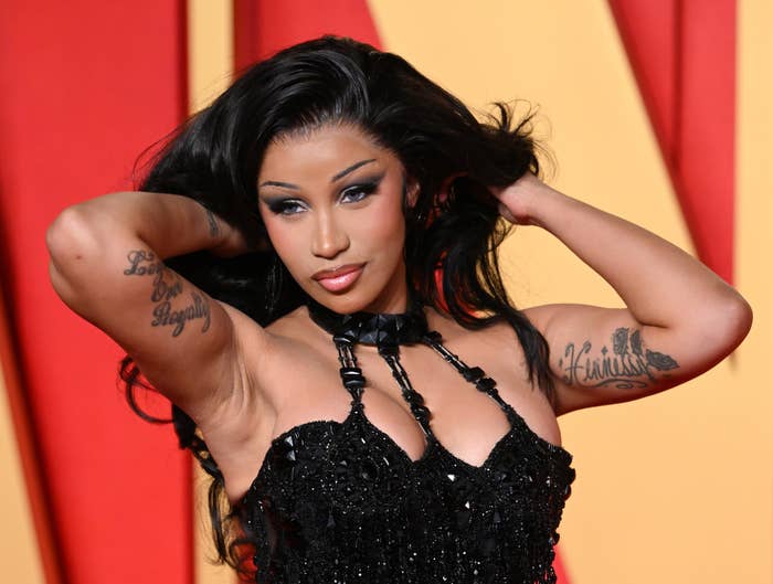 Cardi B poses on the red carpet in a sequined black dress with a high neck