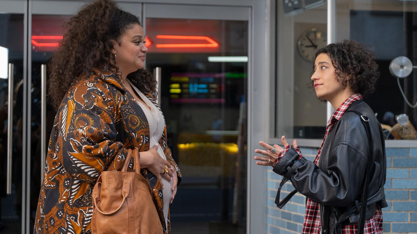 Two women stand outside a diner, engaged in conversation for a scene in a TV show