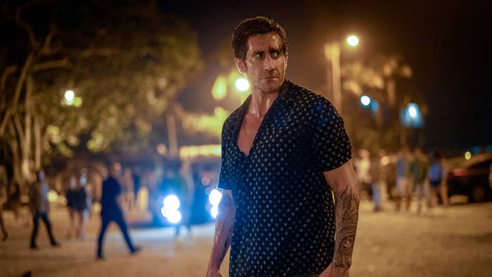 Man in patterned shirt walking confidently on a busy street at night