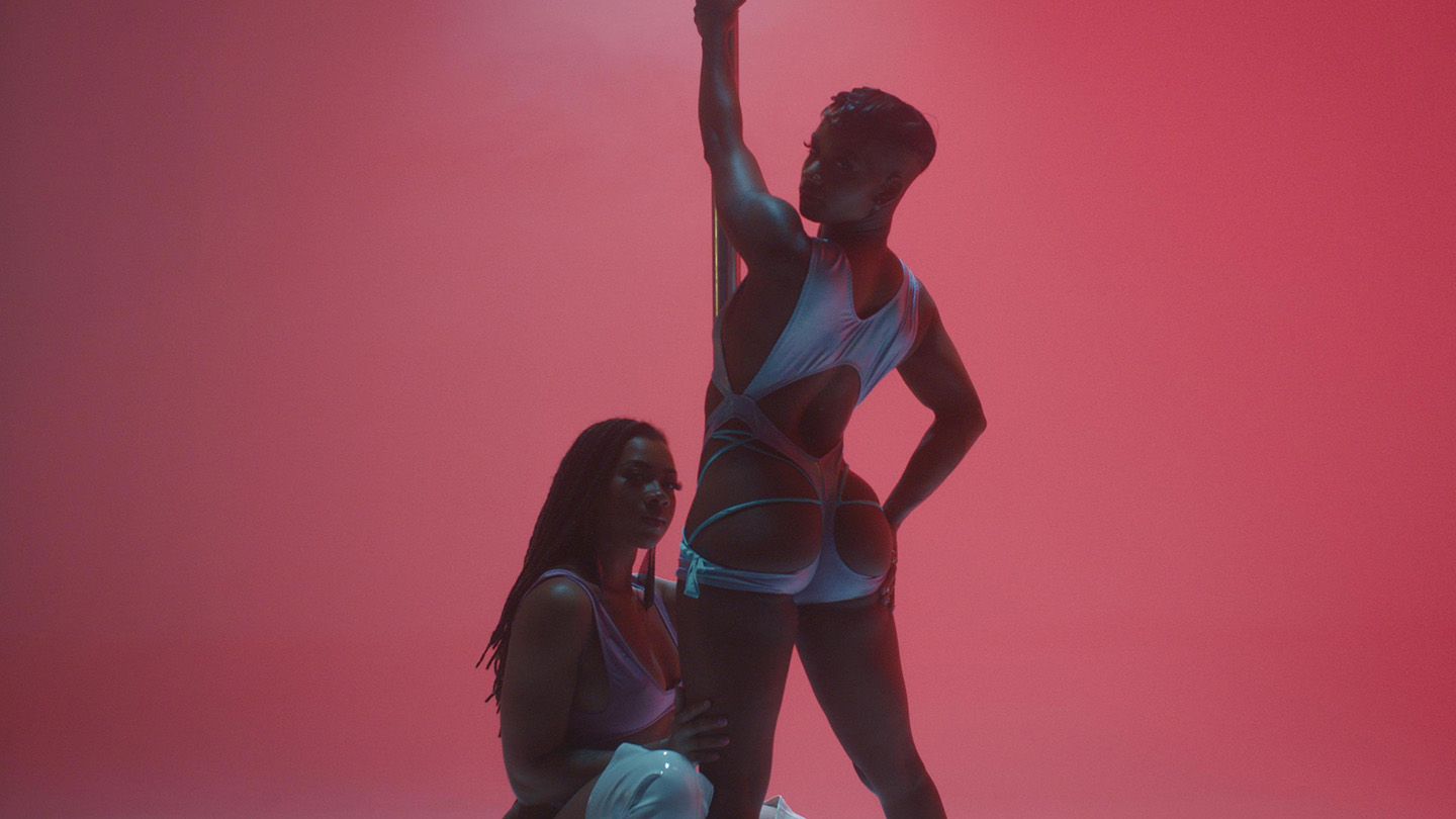 Two models in sportswear posing confidently against a pink backdrop