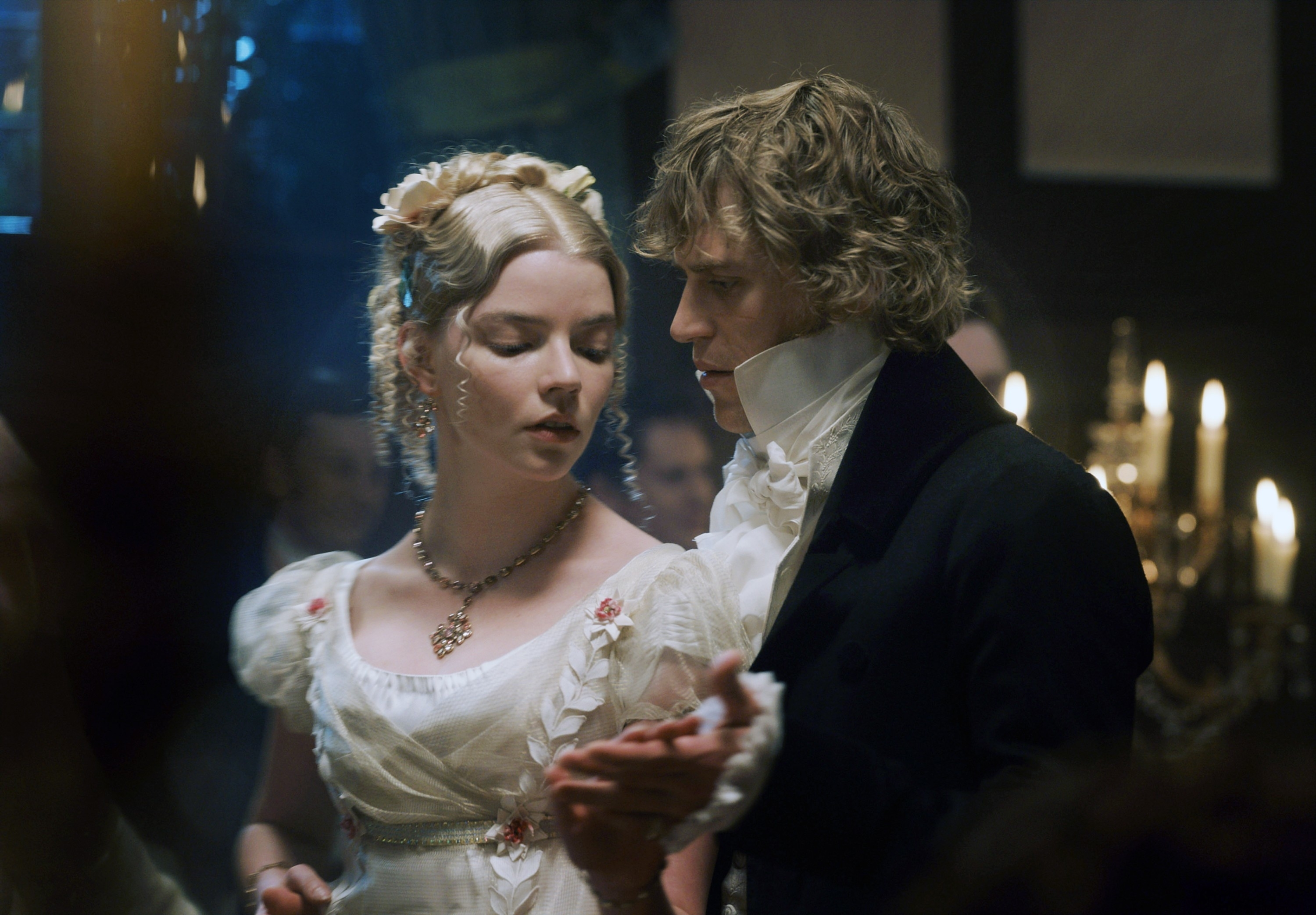 Two actors in historical costumes, as a well-dressed couple, engage in a dance