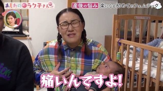 赤ちゃんを抱っこしている人と木製のベビーベッドがある部屋。