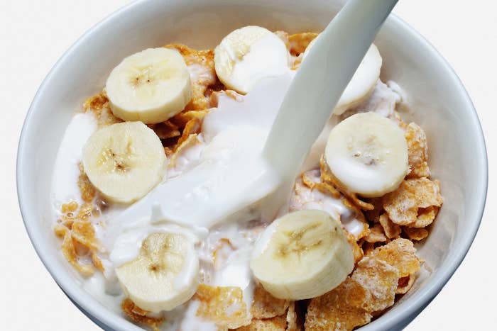 Bowl of cereal with banana slices and milk being poured from above