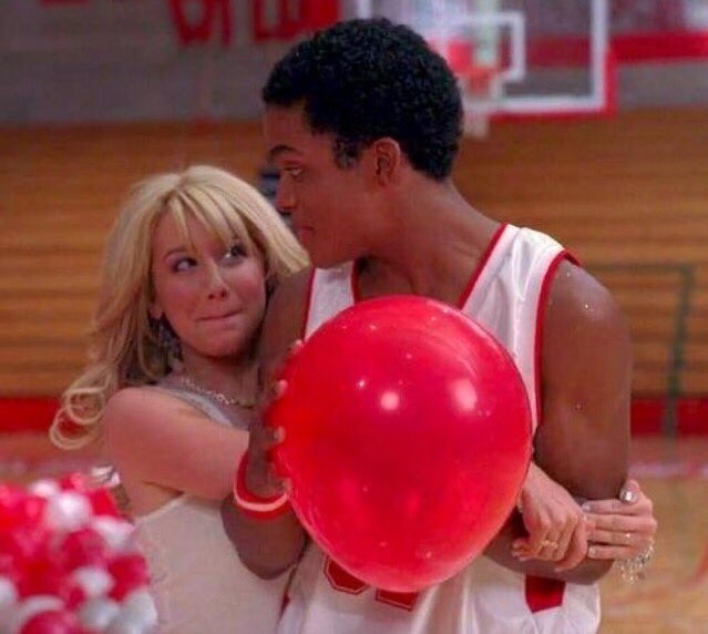 Sharpay and Zeke from High School Musical in gym with basketball. Sharpay looks surprised as Zeke smiles