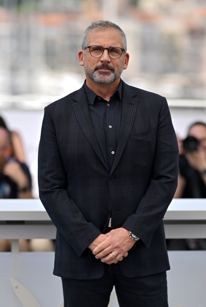 Steve Carell in a pinstripe suit, hands crossed, at an event