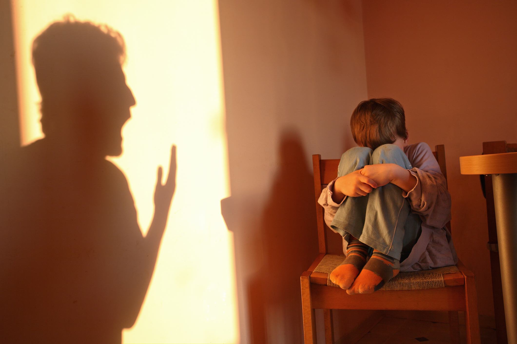 Adult silhouette appears to scold a child sitting with head down, indicating a disciplinary moment