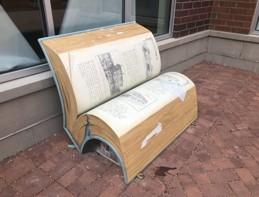Public bench designed to resemble an open book with historical images and text on pages
