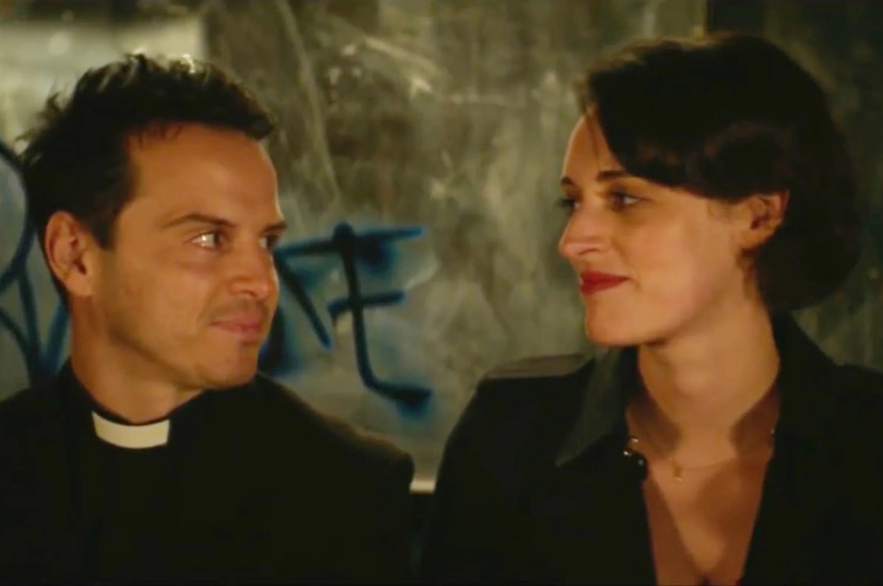 Two characters, a priest and a woman, share a glance with a smile on a TV show