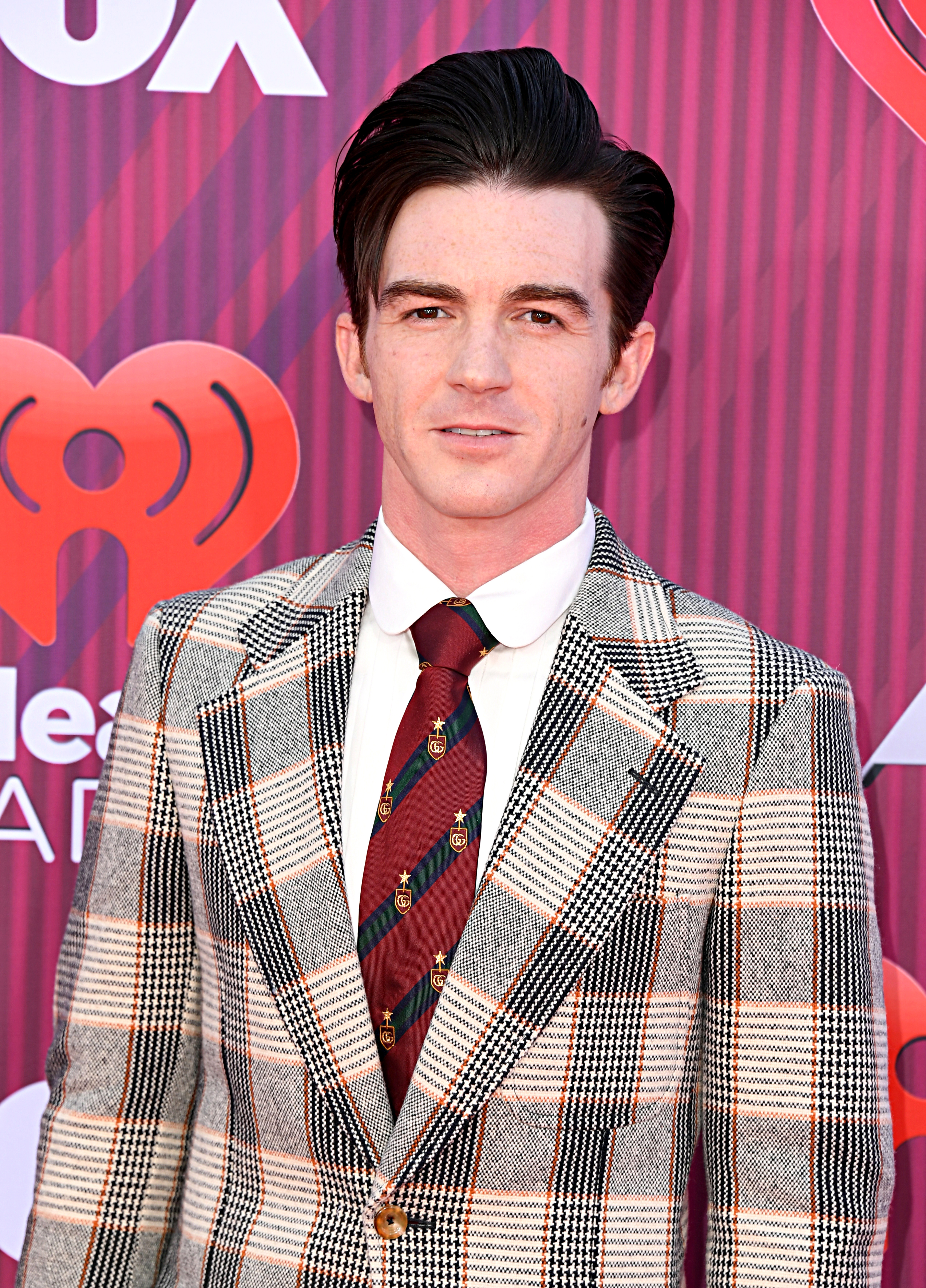 Drake Bell in a plaid suit with a striped tie at an event