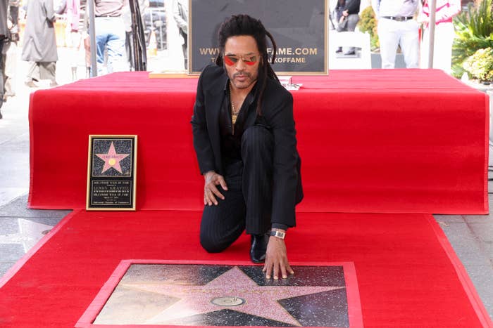 Lenny kneels by his new star on Hollywood Walk of Fame; wearing sunglasses and black attire