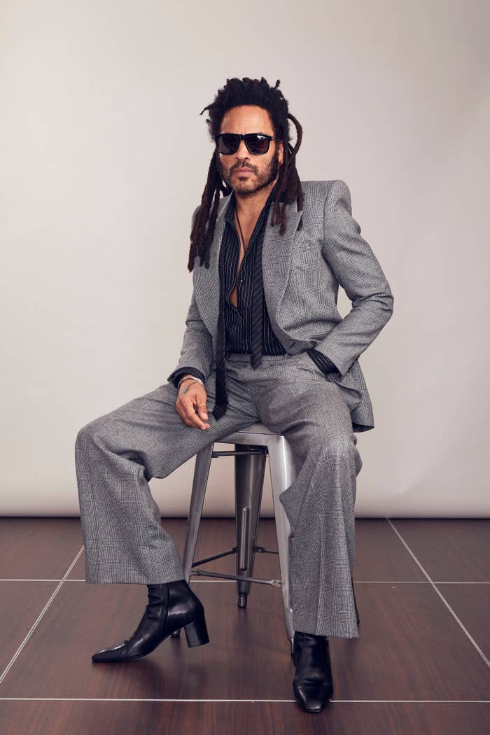 Lenny in a stylish suit with unbuttoned shirt sitting on a stool