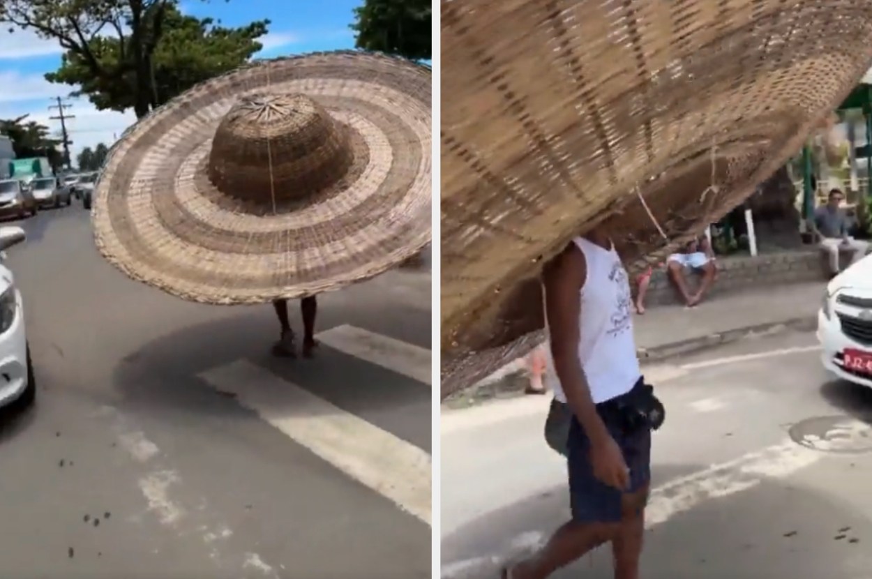 Person walking in street with overly large straw hat covering entire body