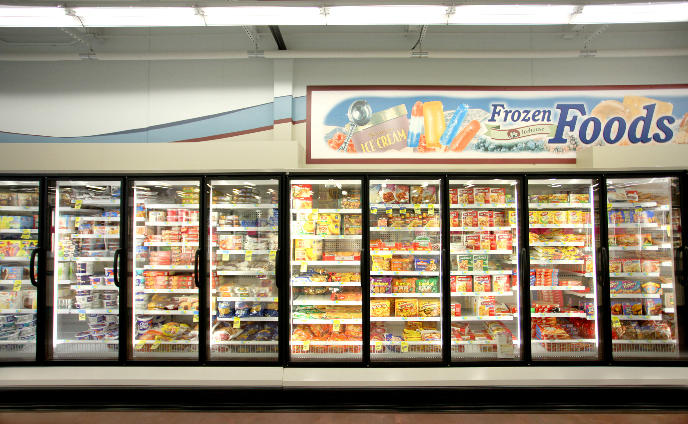 Aisle with a variety of frozen food items displayed in glass door freezers under a &quot;Frozen Foods&quot; sign