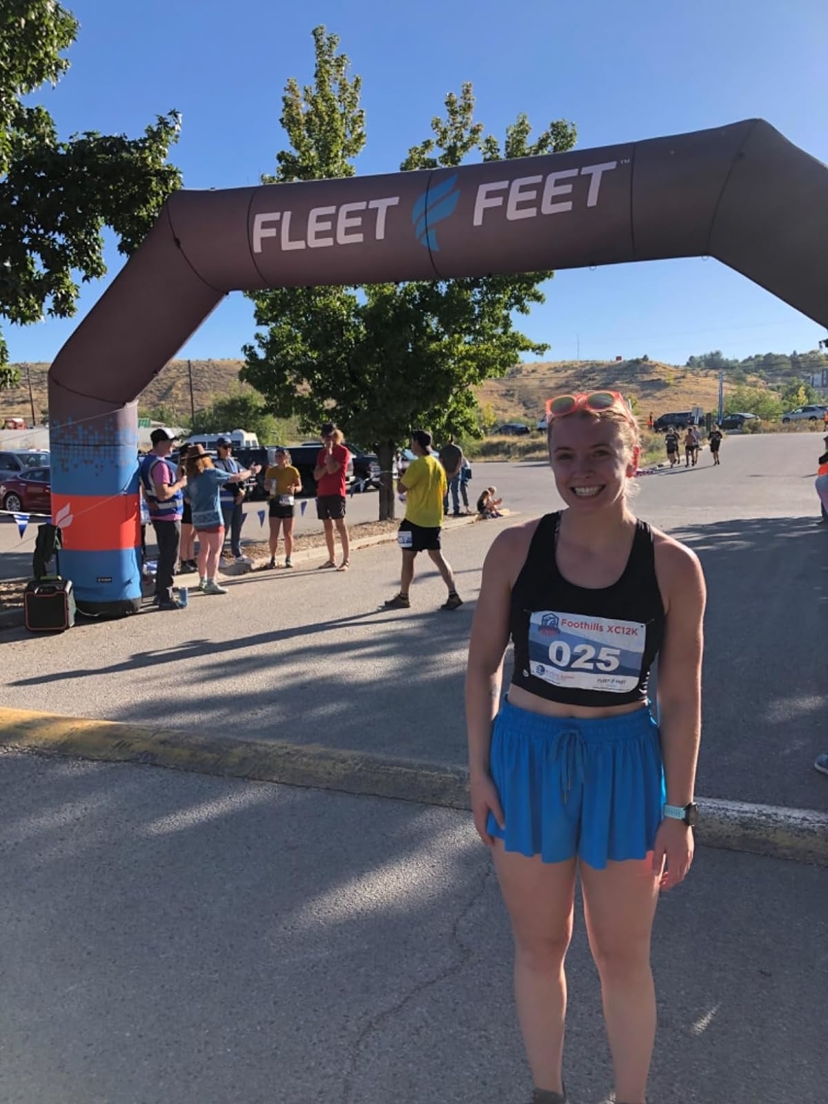 Reviewer in athletic wear smiling at a start line under a &#x27;Fleet Feet&#x27; arch, ready for a race