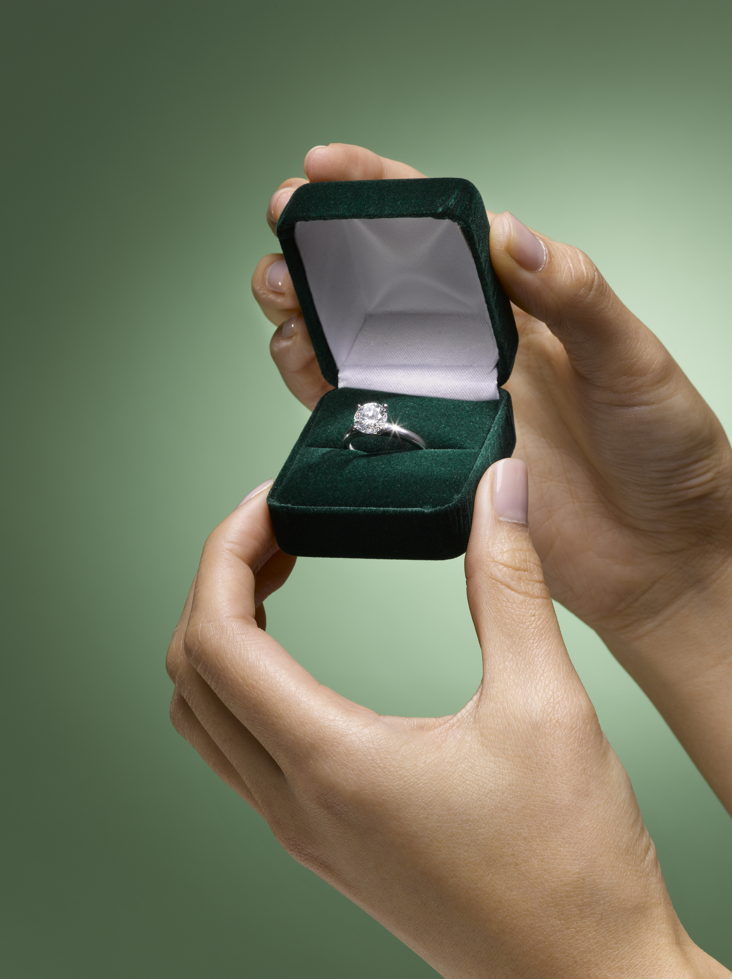 Hands presenting an open ring box with a diamond ring, suggesting a proposal or gift