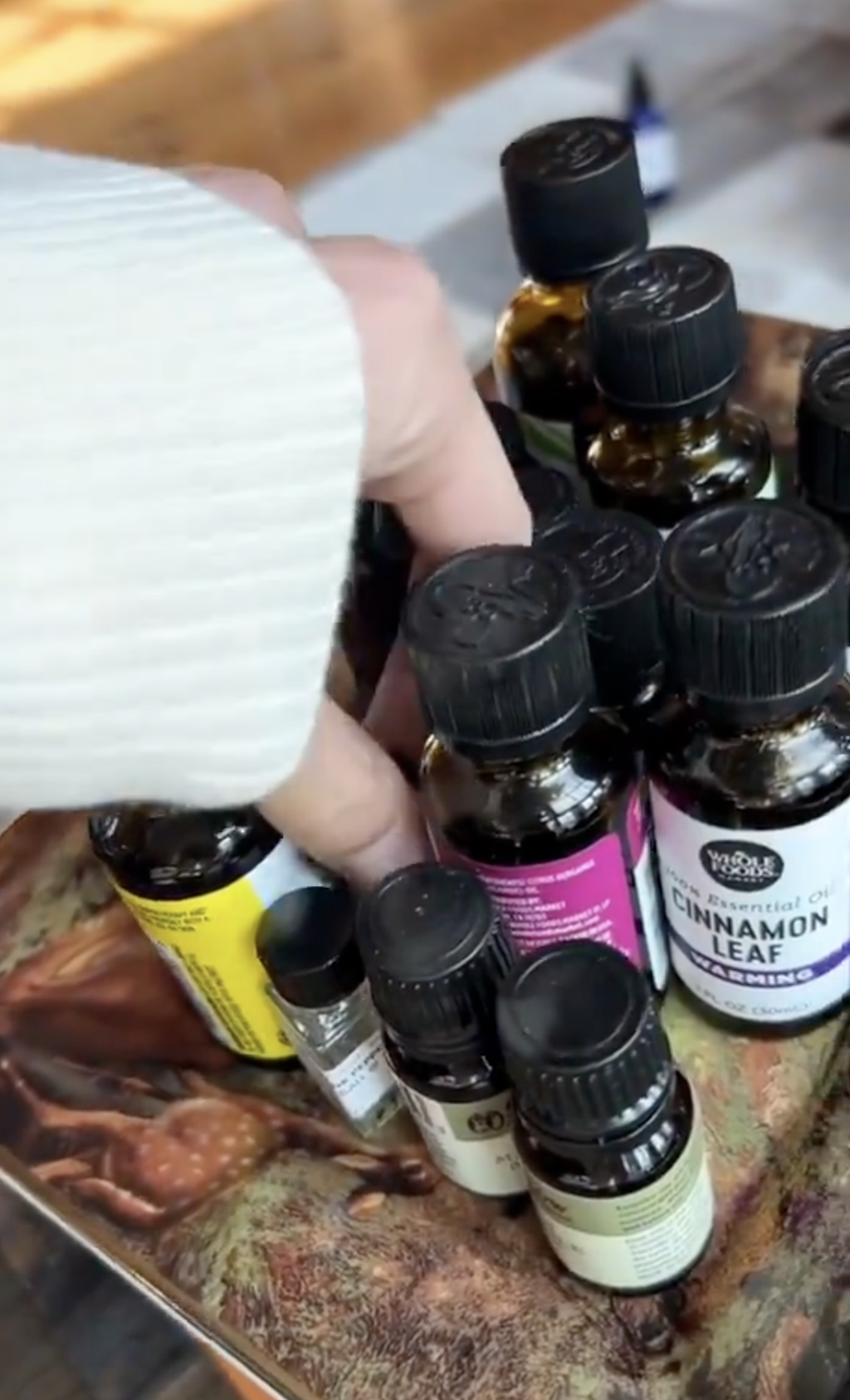 Hand selecting from various essential oil bottles on a tray