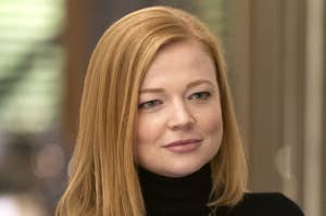 Woman in a black turtleneck with shoulder-length hair smiling