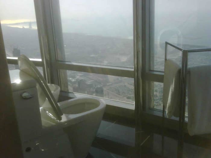 Bathroom with toilet next to floor-to-ceiling windows overlooking expansive view