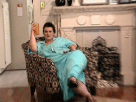 Person lounging on a sofa, holding a juice glass and looking shocked