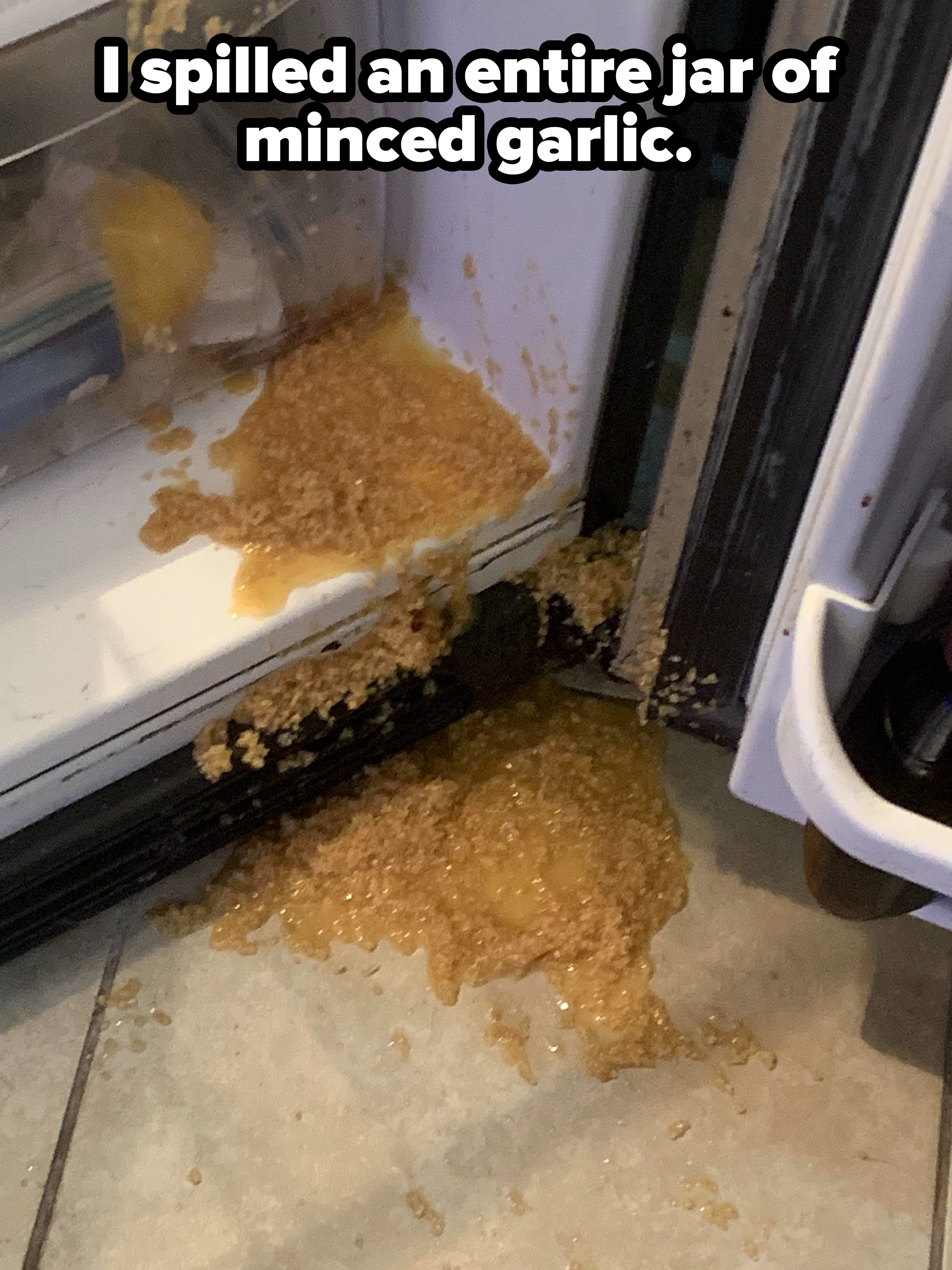 A jar of spilled minced garlic on the floor beside an open microwave door